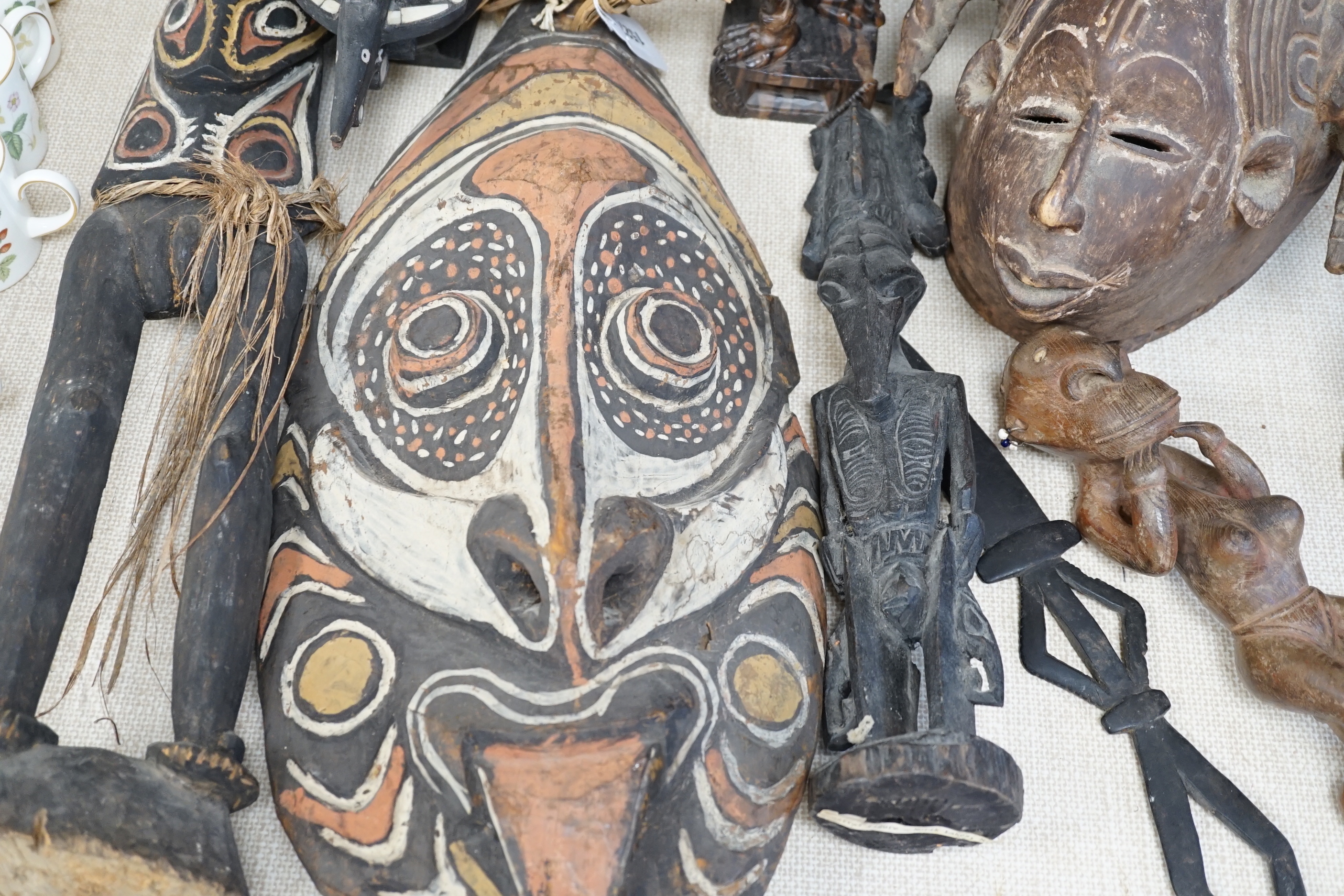 A collection of tribal carvings and masks mostly from Papa New Guinea, largest painted straw mask 86cm high